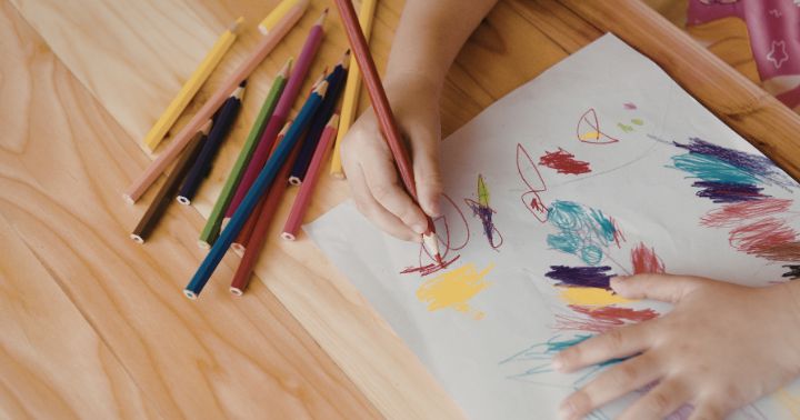 Closeup of a child's hand using a tripod grasp to draw a picture